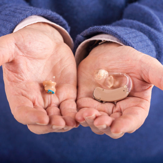 CIC and BTE hearing aids in a man's hands